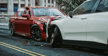 A red car and a white car are both visibly damaged after a collision, with dents and scratches on their surfaces.